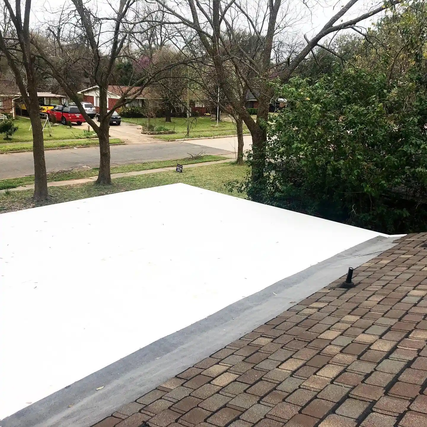 White flat roofing membrane beside asphalt shingles in Shreveport, LA.