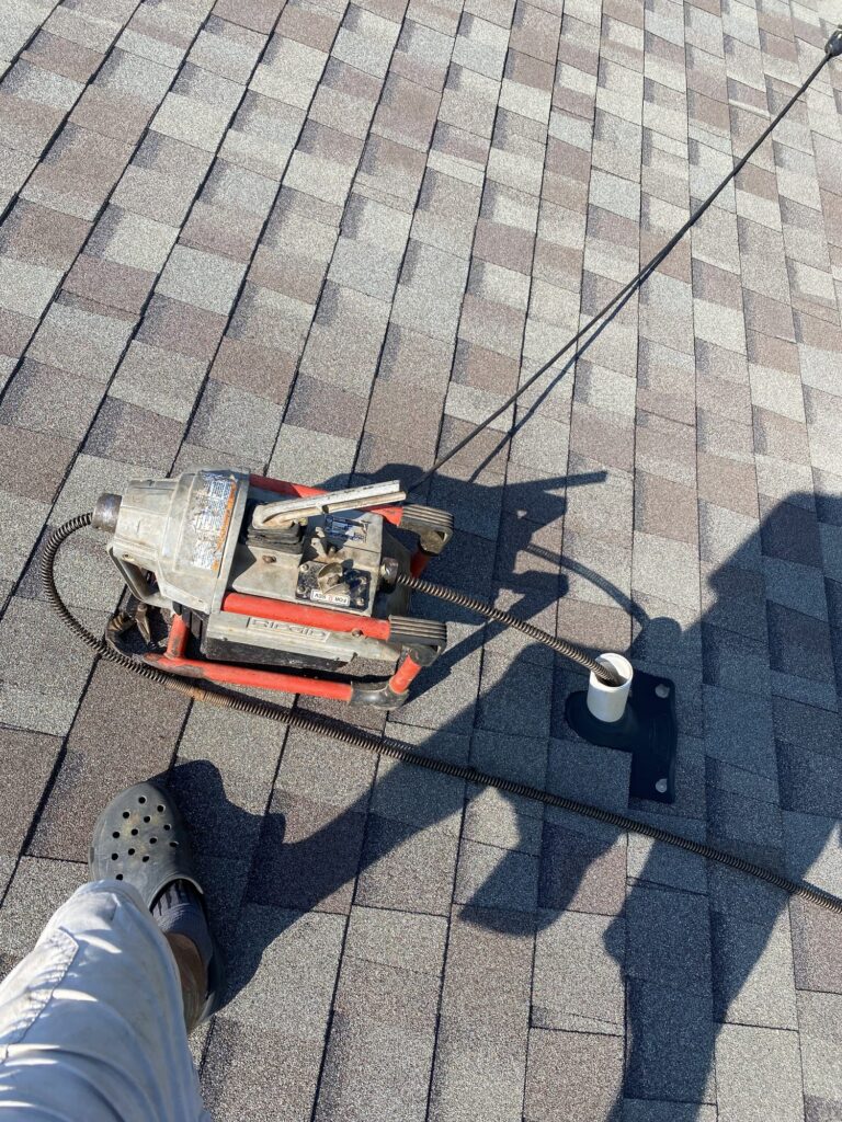 Drain cleaning machine clearing a roof vent stack on a Blue Note Pros service call